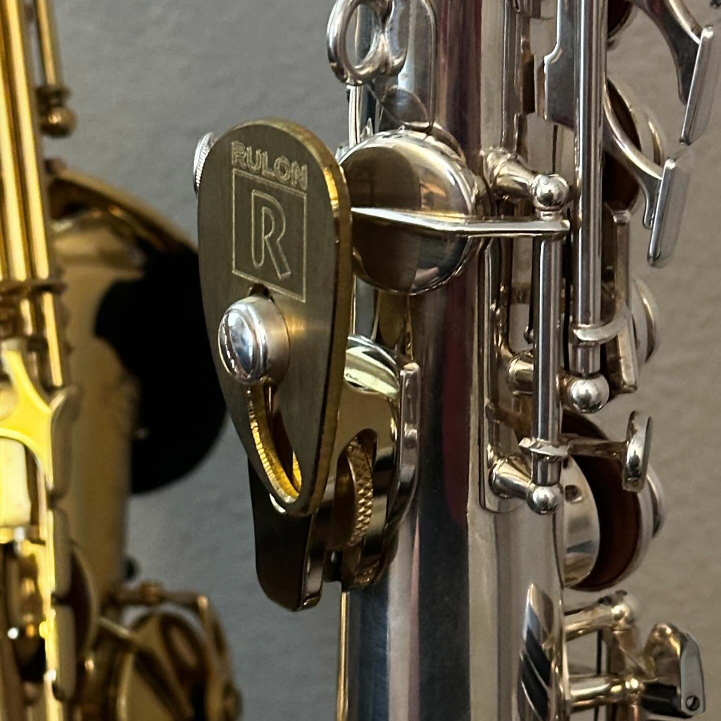 A silver plated soprano saxophone using a RULON saxophone rest mounted to a LAGAN wrist saver. These devices help adjust grip position and thumb placement on the saxophone so the player feels less tension in the wrist and no pain or discomfort from the saxophone thumb hook.