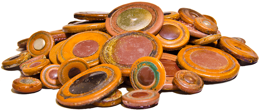 A pile of sticky rotten saxophone pads made of leather. The resonators and pad material are full of green and brown gunk that makes pads sticky