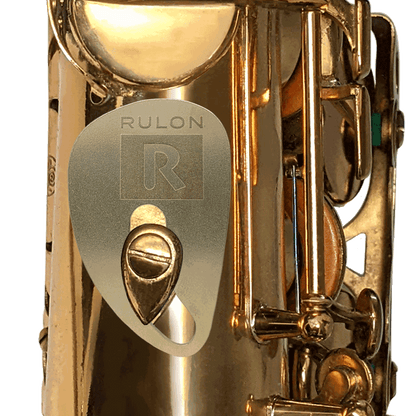 A RULON Saxophone Rest made from tumbled raw brass shown mounted to a tenor saxophone thumb hook screw.
