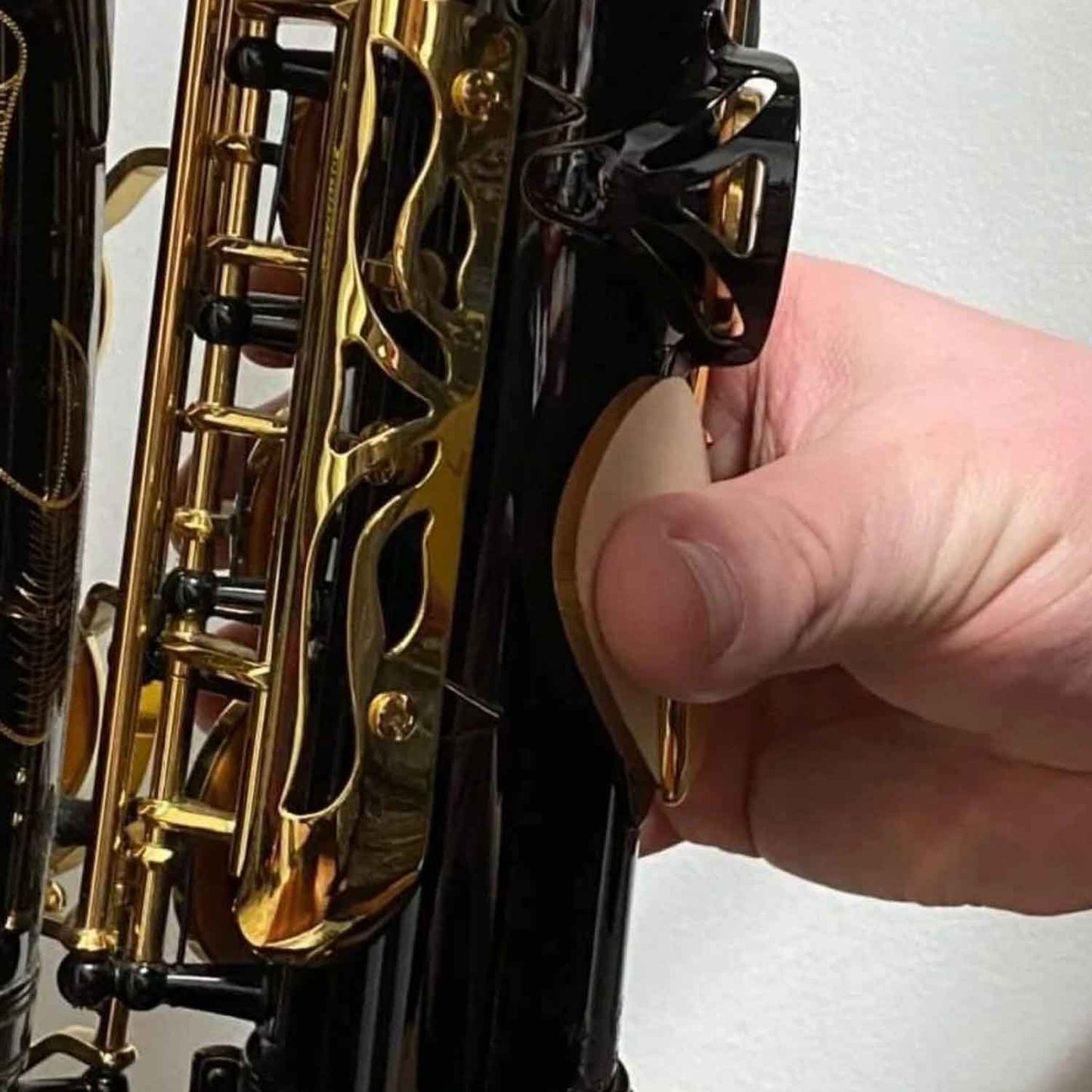 A close up view of the RULON saxophone thumb rest being used with very large hands on an alto saxophone.